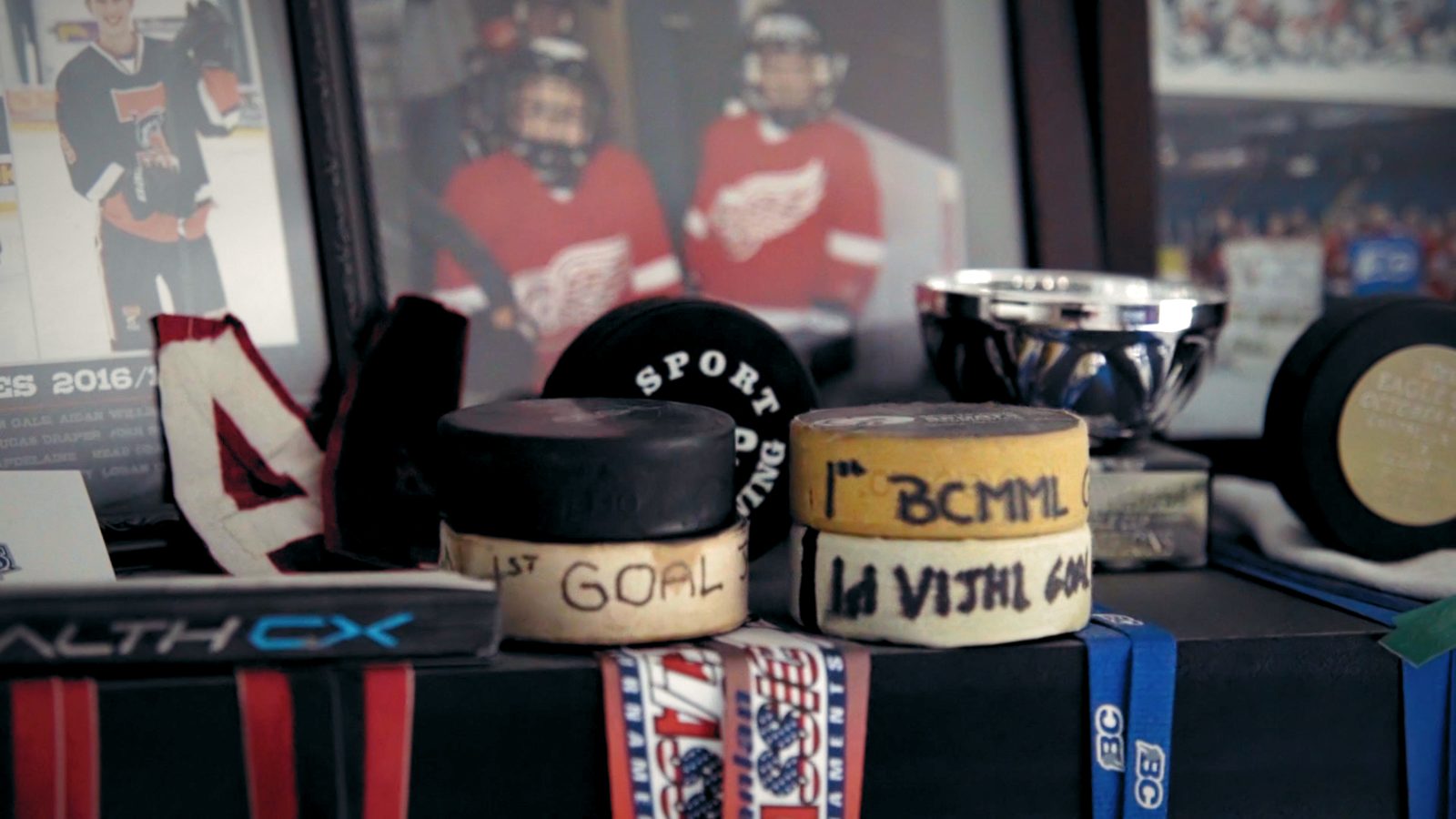 A shelf of first-goal pucks and framed hockey photos